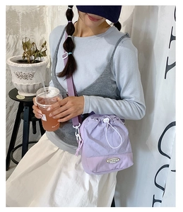 Detail of light purple nylon drawstring bucket bag with adjustable strap and fashion label
