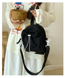 Detail of black drawstring crossbody bag showing adjustable straps and toggle closure