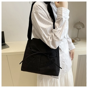 Dettaglio borsa tote in nylon nero con fiocco decorativo e tessuto dalla trama increspata