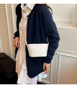 Close-up of a white lychee grain crossbody bag featuring fashion text on the front side