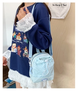 Detail of light blue nylon crossbody bag with drawstring closure and fashion label
