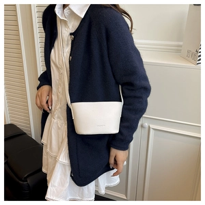 Detail of white lychee pattern crossbody bucket bag featuring fashion logo embossing
