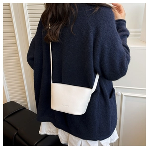 Close-up of a white lychee grain leather bucket bag with embossed FASHION lettering