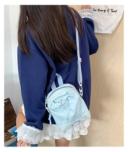 Detail of light blue drawstring mini bag with fashion logo and adjustable strap