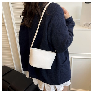 Detail view of white lychee leather bucket bag with embossed FASHION logo on female model