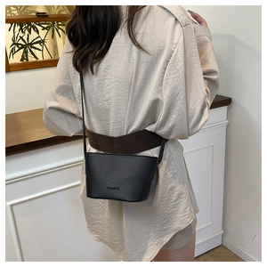 Rear view of model wearing a black lychee texture bucket bag with FASHION lettering