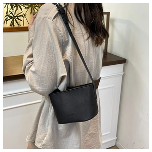 Detail of black lychee texture leather bucket bag with embossed Fashion lettering