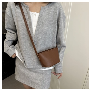 Close-up of brown litchi pattern leather bucket bag with FASHION embossed detail