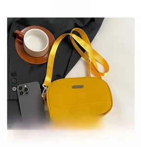 Detail of yellow nylon crossbody bag with metal logo plate and adjustable shoulder strap