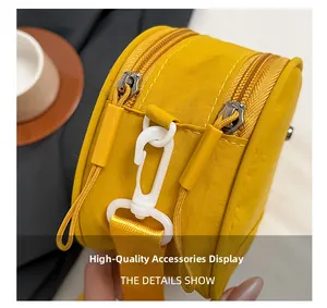 Detail of yellow nylon shell bag featuring dual zippers and durable plastic carabiner