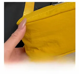 Close-up of vibrant yellow nylon crossbody bag featuring precision white stitching details