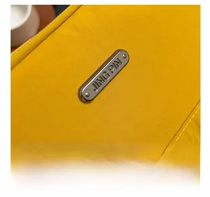 Macro detail of yellow nylon fabric with white stitching and engraved JING PIN metal plate