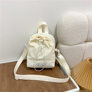 Chic cream nylon drawstring crossbody bag with fashion label and adjustable strap
