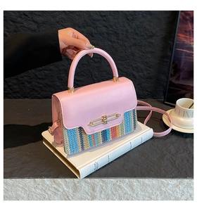 Close-up of pink leather handbag with multi-color woven texture and gold metal lock