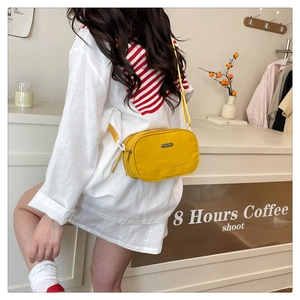 Detail of a bright yellow Oxford shell bag with double zippers and adjustable strap