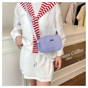 Close-up of lavender nylon crossbody bag with dual-zipper compartments and metal logo