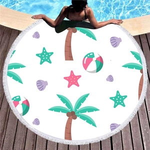 Toalla de playa redonda con estampados tropicales y borlas blancas junto a la piscina