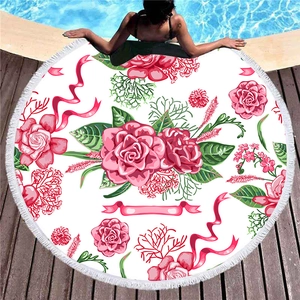 Round beach towel with floral pattern and white tassels on pool wood deck