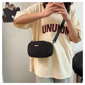 Detail of minimalist black oxford shell crossbody bag with adjustable wide strap on model