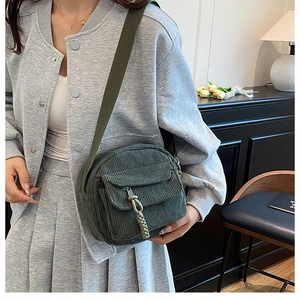 Detail of dark green corduroy crossbody bag featuring canvas strap and front pocket