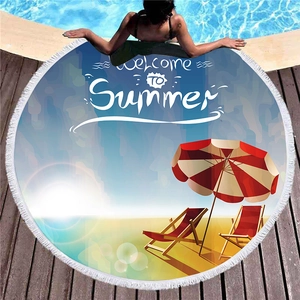 Circular beach towel with tassels featuring a Welcome To Summer print by a pool deck