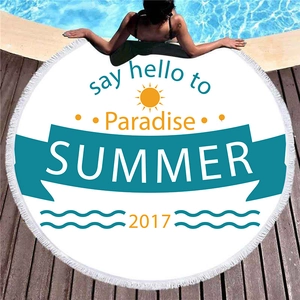 Thick circular Summer fringe beach towel on wood deck by a sparkling swimming pool