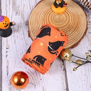 Close-up of orange Halloween ribbon with black cat and star prints on a rustic wood base
