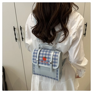 Detail of blue and white checkered backpack with apple embroidery on a model