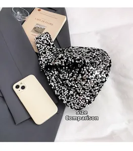 Detail van zwarte handtas met pailletten en glittertextuur naast een smartphone getoond