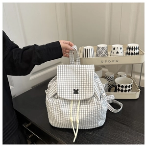 Detailed close-up of a black and white gingham backpack with drawstring and flap closure