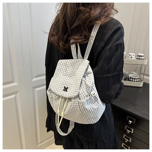 Detail of grey plaid canvas backpack with drawstring closure and practical side pockets