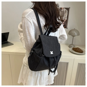 Detail of drawstring backpack with black grid pattern and white buckle closure