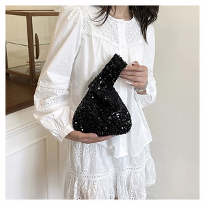 Close-up of black sequin knot bag on model wrist highlighting the shimmering texture