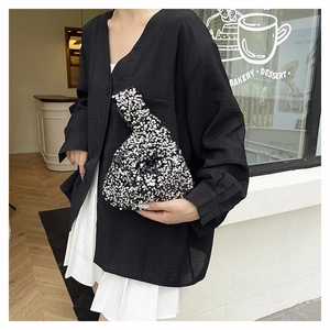 Close-up of sparkling black and white sequins on a stylish triangular wrist bag for women