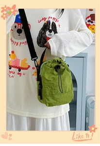 Detail of green nylon crossbody bag showing the drawstring closure and textured fabric
