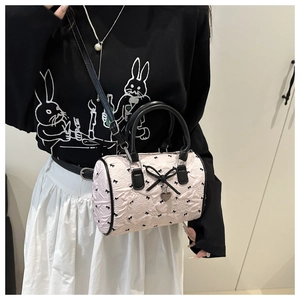 Close-up of pink seersucker Boston bag with black bow prints and heart pendant