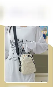 Model wearing off-white lightweight crossbody phone bag with drawstring closure