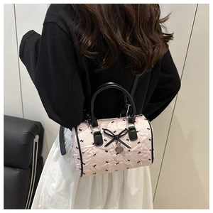 Detailed close-up of pink seersucker Boston bag with black bows and heart pendant