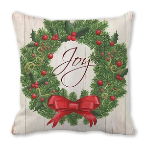 Detail van kerstkrans kussensloop met Joy-tekst en rode strik op wit houtstructuur