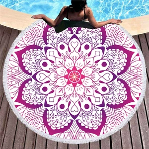 Round mandala beach towel with white tassels on wooden deck by a pool