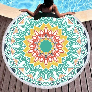 Round mandala beach towel with white tassels and vibrant geometric patterns on wood deck