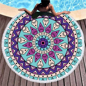 Round mandala beach towel with white tassels and bohemian geometric pattern on pool deck