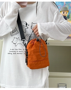Detalle de bolso bandolera naranja de nailon impermeable con cordón y cremallera
