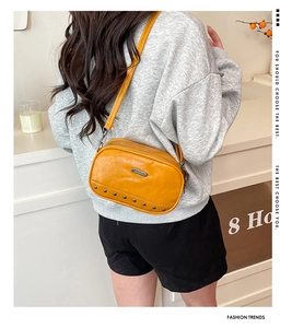 Detail of yellow mustard square crossbody bag with silver rivets and adjustable strap