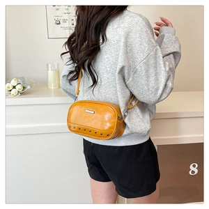 Detailed view of the ginger yellow shell bag featuring decorative bottom metal rivets