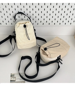 Detail of lightweight drawstring crossbody bag showing side zipper and nylon texture