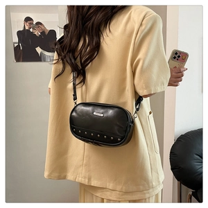 Close-up of black crossbody bag with metal rivets and JING PIN brand plaque detail