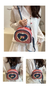 Detail of red checkered mini backpack featuring lace heart patch and cherry embroidery