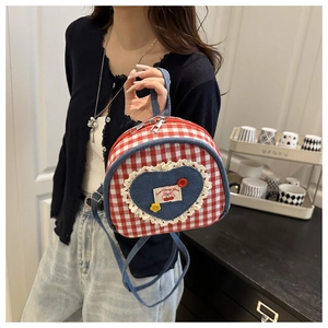 Détail d'un mini sac à dos avec patch coeur en jean et broderie cerise décorative