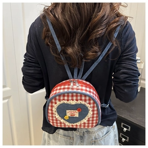 Detail of mini quilted backpack with denim heart patch and red plaid fabric texture